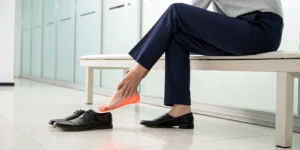 A person holding their foot because the heel hurts.